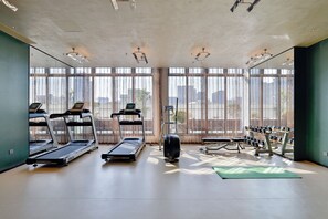Un gimnasio con cintas de correr, una prensa de pesas y un estante con mancuernas.