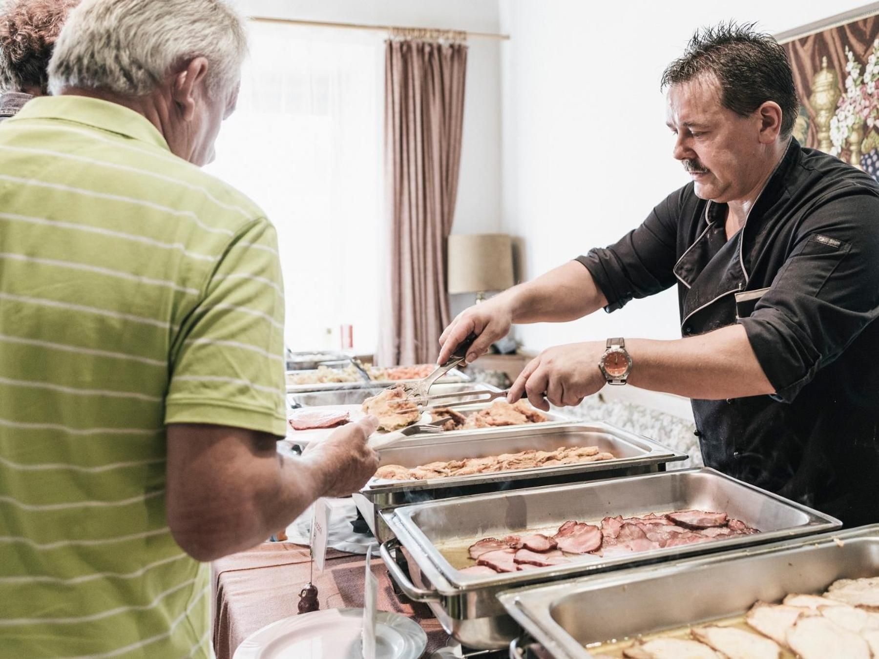 Un aparador de buffet amb diverses safates de menjar, incloent carn tallada i possiblement altres plats.