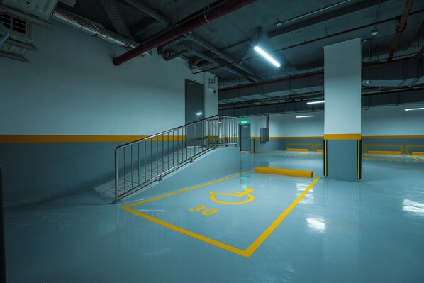 Eine Parkgarage mit einem rollstuhlgerechten Stellplatz, der auf dem Boden markiert ist.