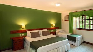 Una camera con un letto grande, un letto più piccolo, due comodini e una finestra con tende.