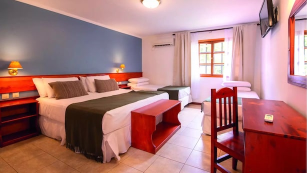 Una camera d'albergo con un letto, comodini, una scrivania, una sedia e un televisore.