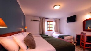 Una camera d'albergo con due letti, una scrivania, una sedia, una televisione e una finestra con tende.