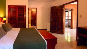 Una camera d'albergo con un letto, una panca e due porte che danno su altre stanze.