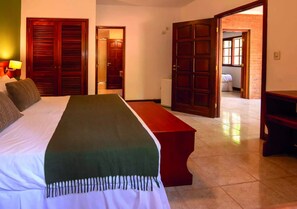 A hotel room with a bed, a bench, and two doors leading to other rooms. - Hotel Y Cabañas Del Leñador (Puerto Iguazú)