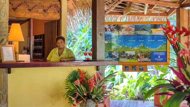 A reception desk with a map and information board, surrounded by tropical plants. - Shawandha Hotel (Cahuita)