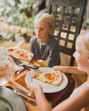 A dining table with a pizza, a knife, and a glass pitcher. - Shawandha Hotel (Cahuita)