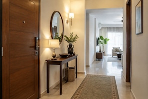 A hallway with a wooden door, a console table with a lamp, a mirror, and a potted plant. - Royal Garden Boutique Hotel (Dhaka)