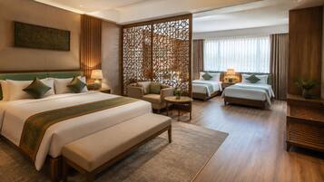 A hotel room with a large bed, two smaller beds, a sofa, a desk, and a decorative partition.