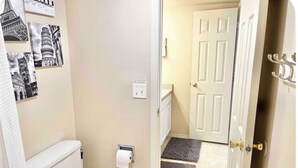 A bathroom with a toilet, a towel rack, and a door leading to a hallway. - Private Suite - Pacman Arcade, USAFA, Yard, AC, Espresso Machine, Kids Playroom (Monument)
