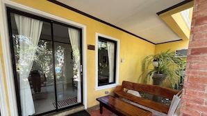 Un banco frente a un edificio amarillo con puerta corredera de vidrio y ventana.