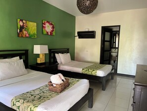 A hotel room with two beds, a nightstand with a lamp, a wall-mounted shelf, and a door leading to a bathroom. - Puerto Del Sol Beach Resort And Hotel Club (Bolinao)