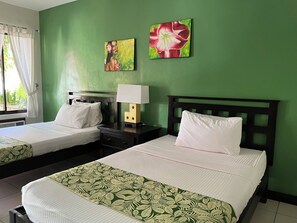 A hotel room with two beds, green walls, and two floral paintings. - Puerto Del Sol Beach Resort And Hotel Club (Bolinao)