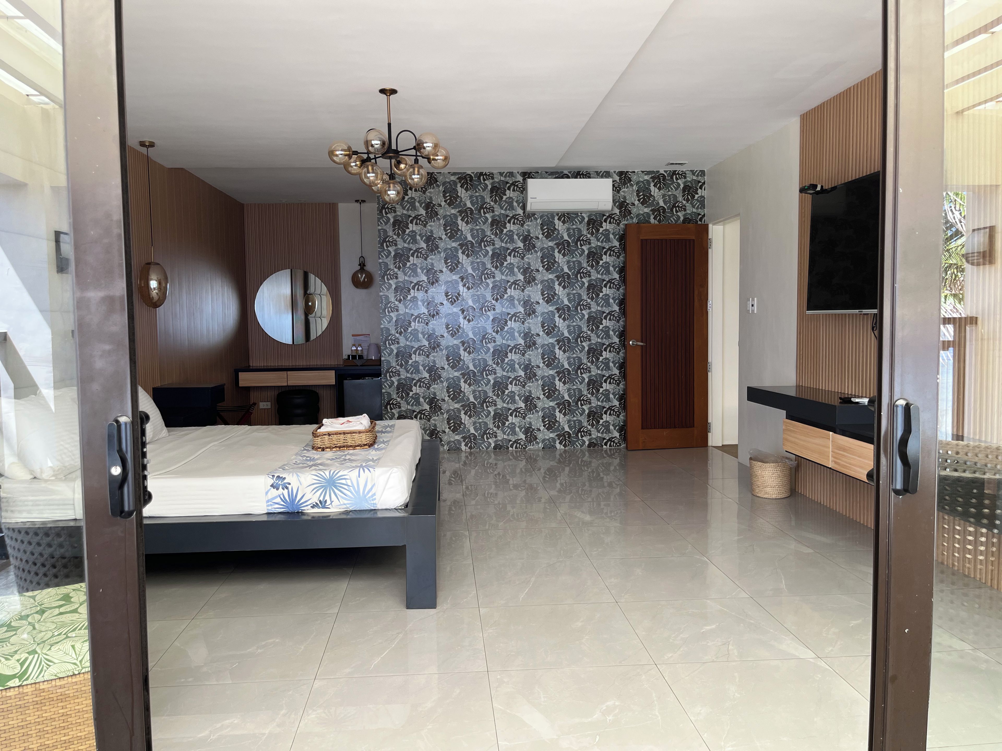 Un dormitorio moderno con cama, cómoda, espejo y televisor.