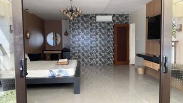 Un dormitorio moderno con cama, cómoda, espejo y televisor.