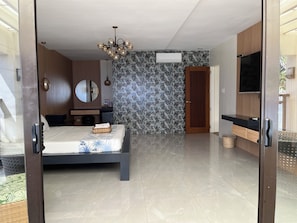 A modern bedroom with a bed, a dresser, a mirror, and a television.
