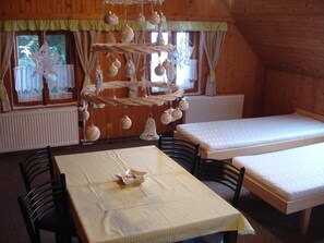 Una habitación con paredes de madera, una mesa con mantel a cuadros, dos camas y un adorno colgante.