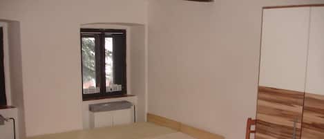 Un dormitorio con una cama individual, una ventana, un radiador y un armario.