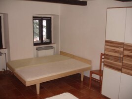 Un dormitorio con una cama individual, una ventana, un radiador y un armario.