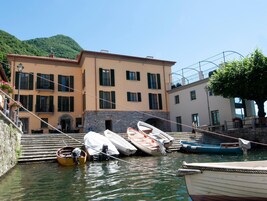 Una propiedad frente al agua con un edificio que cuenta con varios balcones, una escalera de piedra que lleva a un muelle y varias embarcaciones amarradas en el muelle.