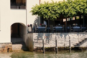 Un restaurante frente al agua con terraza, una escalera de piedra y vistas al mar.