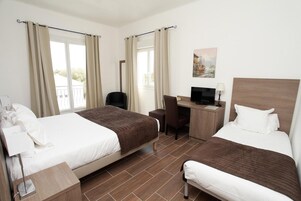 Quarto de hotel com duas camas, uma escrivaninha, uma cadeira e uma televisão.