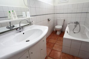 Un baño con lavamanos doble, inodoro y bañera.