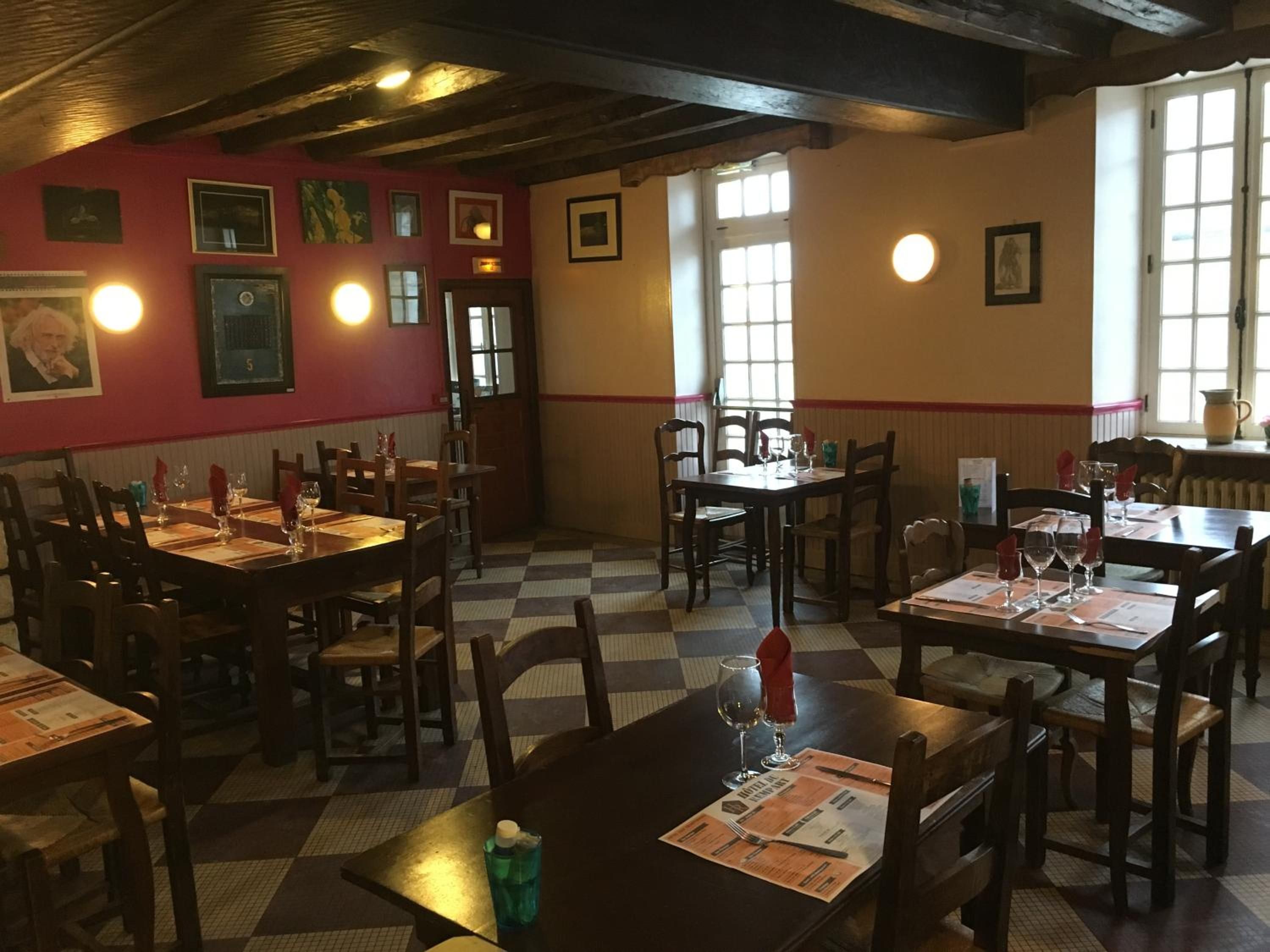 Ein Restaurantinneres mit Holztischen und -stühlen, einem karierten Boden und gerahmten Bildern an den Wänden.