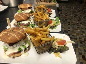 Una comida con hamburguesas, papas fritas y ensaladas sobre una mesa.