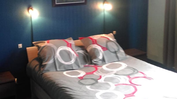 Quarto com cama, duas luminárias de cabeceira, um quadro na parede e uma janela.