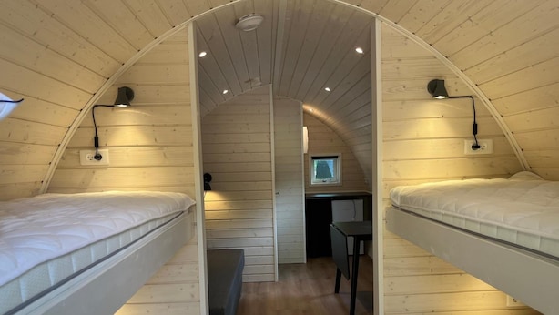 A compact, single-story wooden cabin with bunk beds, a small desk, and a window. - Sportspark Blaavandshuk Resort (Oksbol)