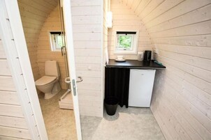Una cabaña pequeña y de una sola habitación con inodoro, kitchenette y ventana.