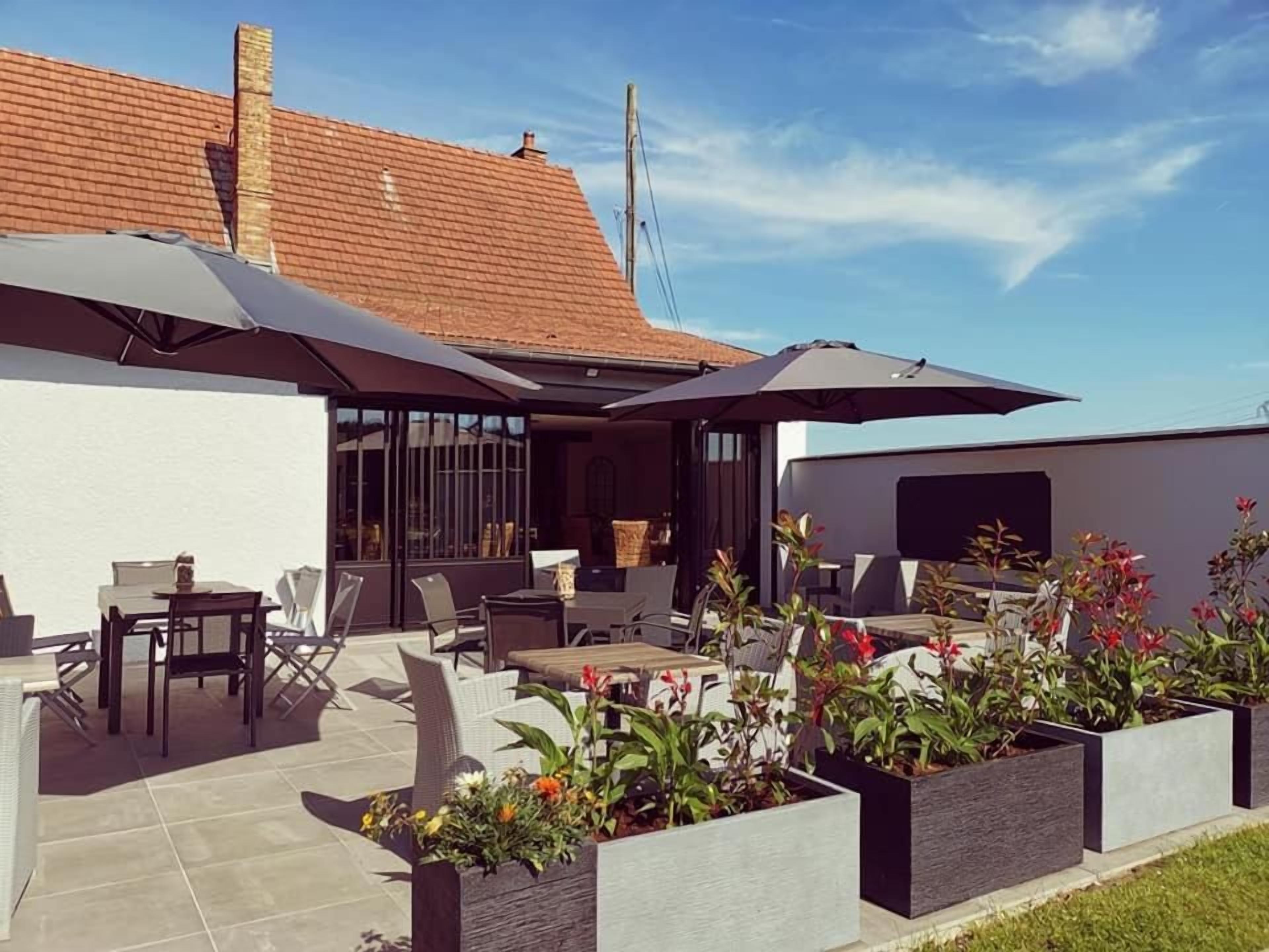 An outdoor patio with seating, planters, and a building with a tiled roof.