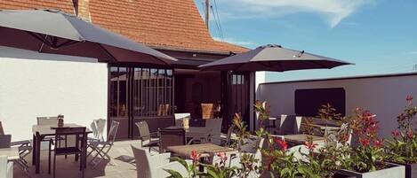 An outdoor patio with seating, planters, and a building with a tiled roof.