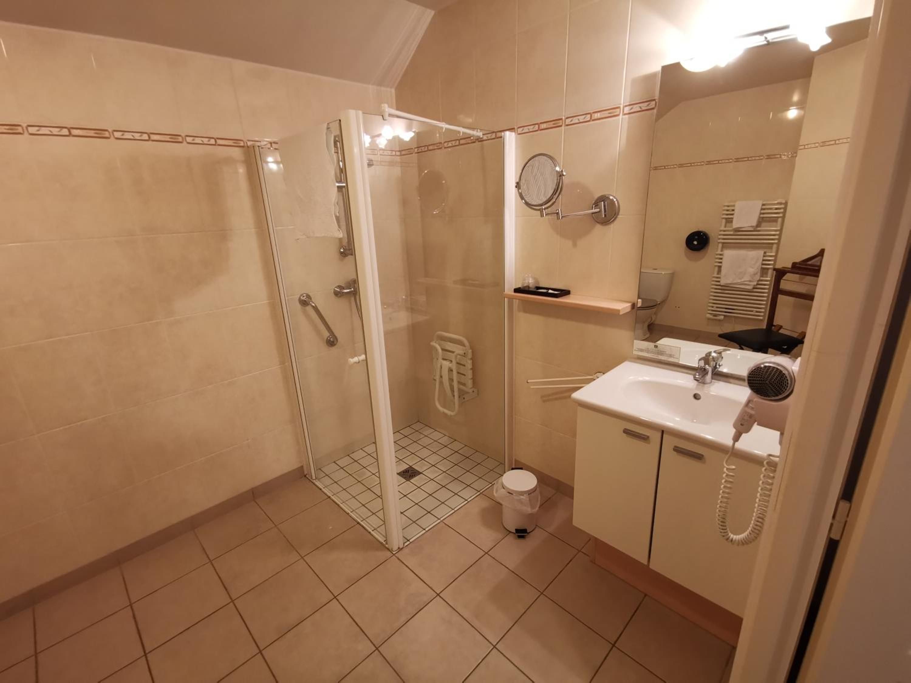 Ein Badezimmer mit Duschkabine aus Glas, Waschbecken und Fön sowie Toilette.