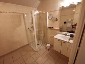 Un baño con cabina de ducha de vidrio, lavamanos con secador de pelo y un inodoro.