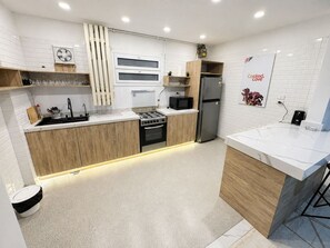 Eine moderne Küche mit weißen Fliesen im U-Bahn-Stil, Holzschränken, einem Edelstahlkühlschrank und einem Einbauofen.