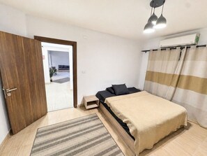 A bedroom with a bed, a nightstand, a door, and a window with curtains. - Al Motameyez Stylish 2BR Retreat w/ Private Garden (Giza)