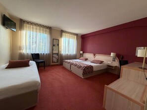 Habitación de hotel con dos camas, un escritorio, una silla, un televisor y un espejo.