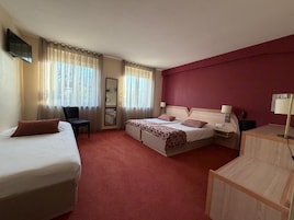 Habitación de hotel con dos camas, un escritorio, una silla, un televisor y un espejo.