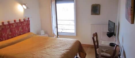 Un dormitorio con cama, una silla, televisor y ventana.