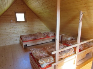A small, single-room cabin with two bunk beds, a small window, and wooden walls. - Rybárská Chata U Sumce (Stribro)