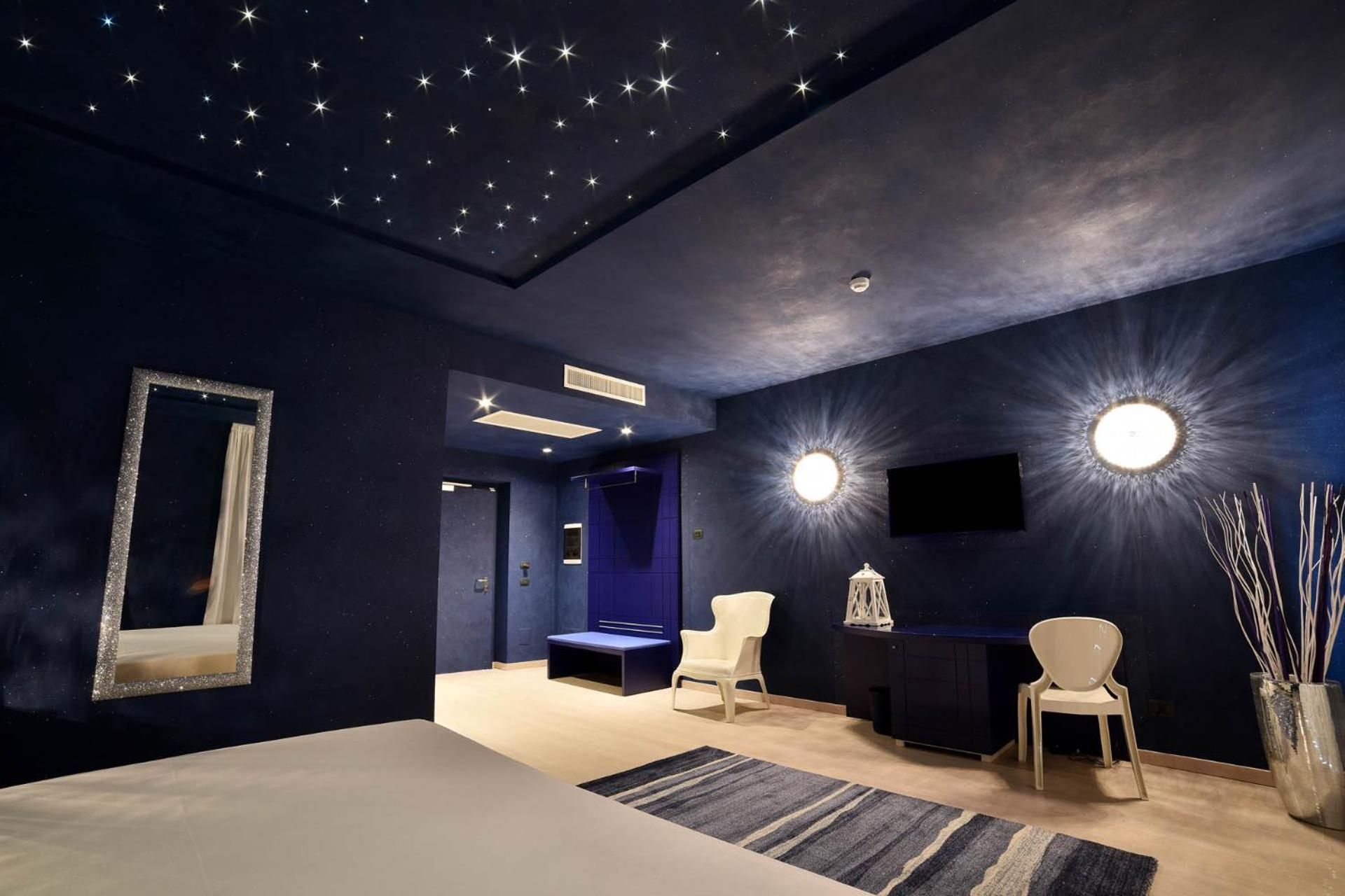 Una habitación con techo estrellado, un espejo grande y dos sillones.