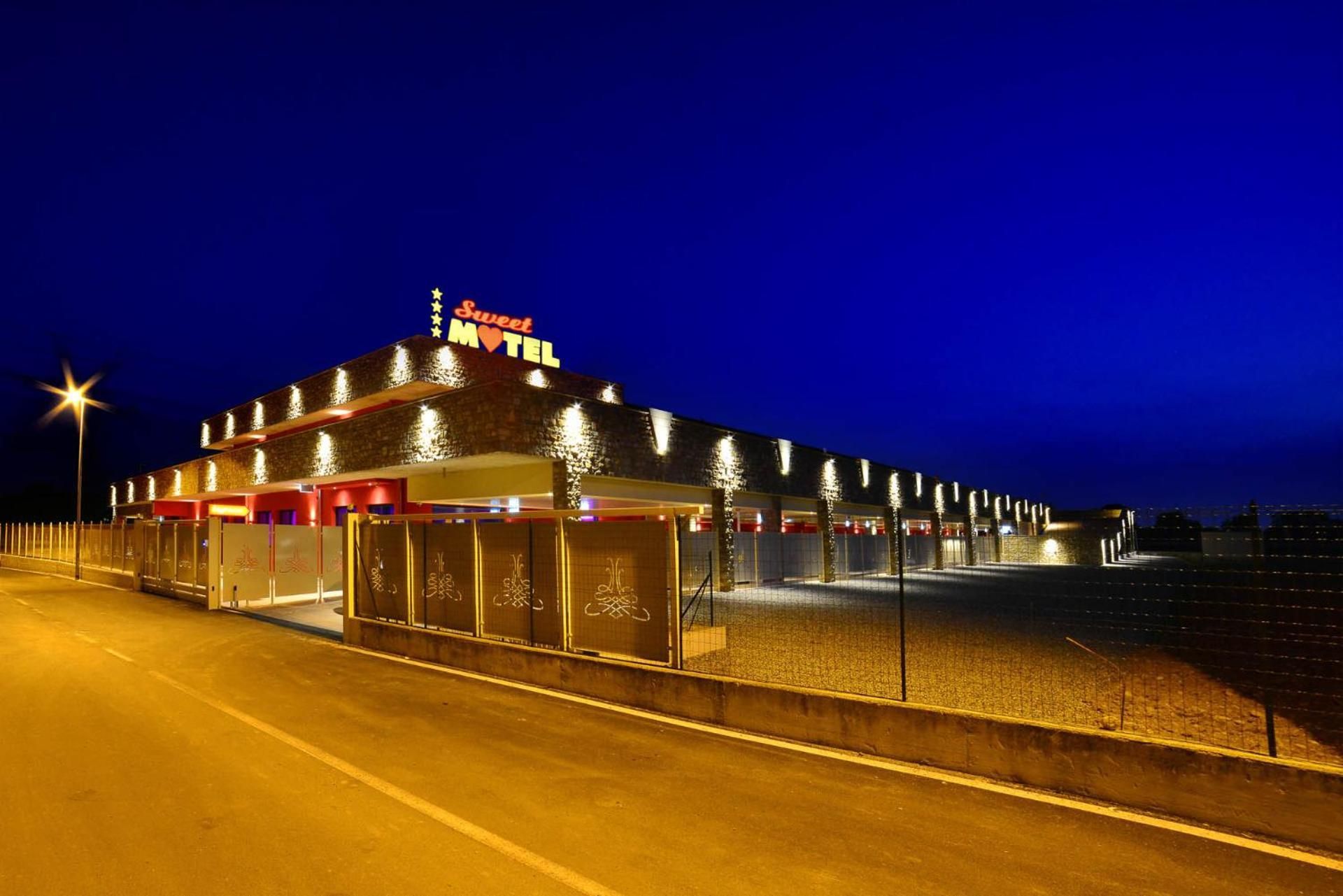 Un motel con una fila de habitaciones, un cartel luminoso y un área de estacionamiento.