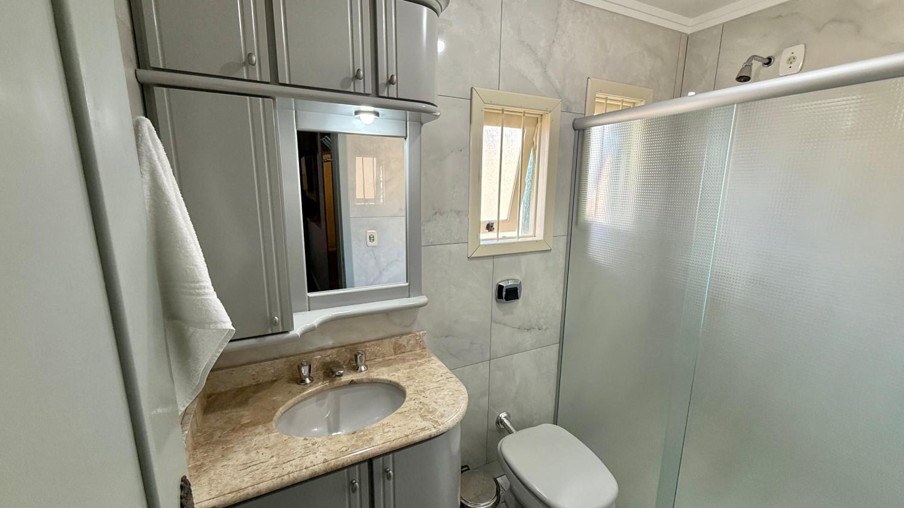 A bathroom with a sink, mirror, toilet, and shower.