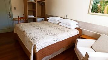 Un dormitorio con cama, armario de madera, ventilador de techo y un cuadro en la pared.