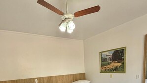 A hotel room with two beds, a ceiling fan, a painting on the wall, and wooden flooring. - Pousada Tedesco (Bento Gonçalves)