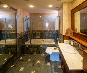 Un baño moderno con ducha de vidrio, una bañera independiente, tocador con lavamanos y un espejo grande.
