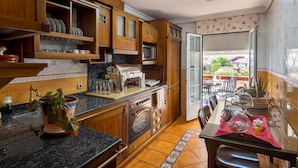 A kitchen with wooden cabinets, a countertop, and a dining area with a table and chairs. - El Descanso De Wendy (Astorga)