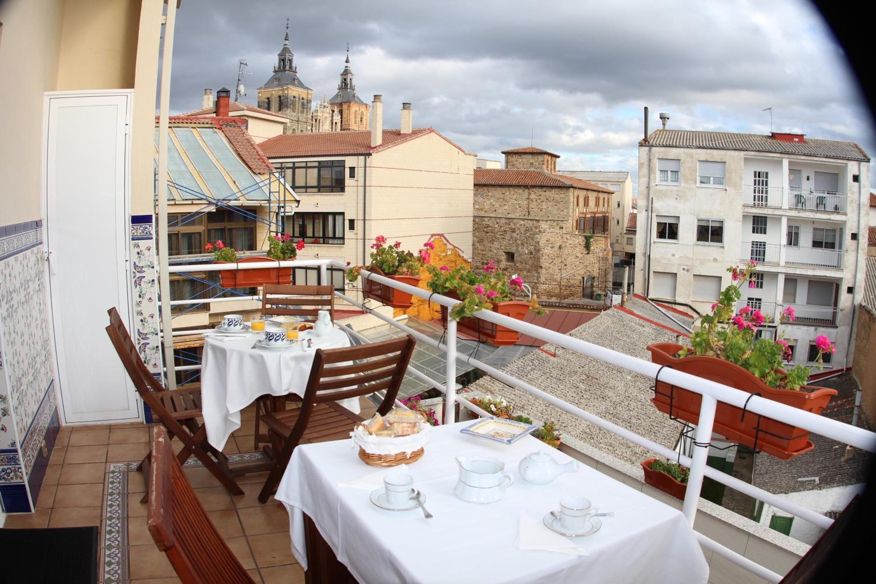 A balcony with a table set for breakfast, overlooking a cityscape with historic buildings.