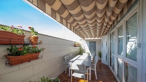 A sunlit patio with a tiled floor, a white table with chairs, and potted plants on the wall. - El Descanso De Wendy (Astorga)